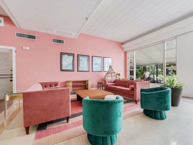 A lobby seating area with pink sofas and green chairs