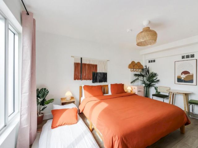 A wide view of a brightly lit hotel room with a large bed, nightstands, and a sitting area.