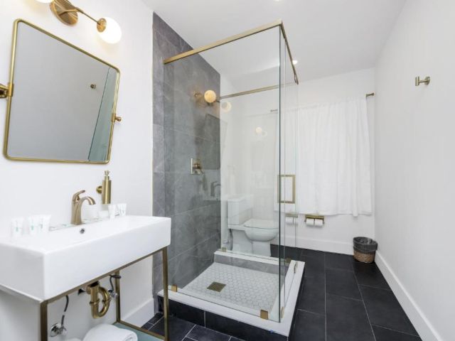 A modern bathroom with a glass-enclosed shower, white sink, and gold fixtures.