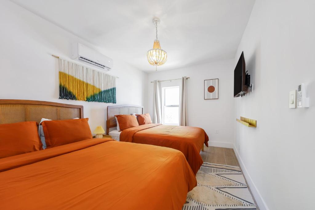 A bright and clean hotel room with two beds, a TV on the wall, and a window with curtains.