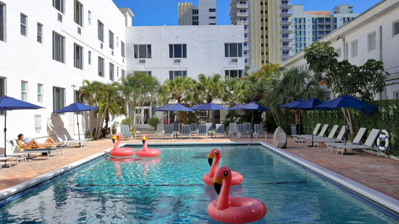 A pool with flamingo floats and lounge chairs